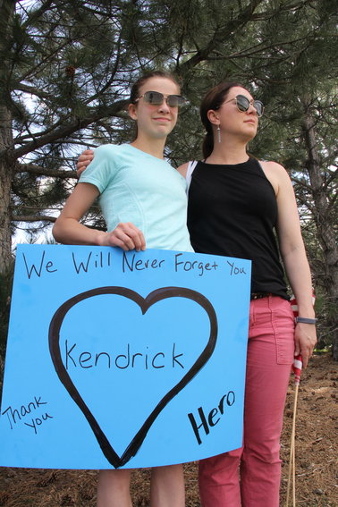 A mother and daughter, who did not want to be named, stand along the road awaiting a motorcade of Jeeps driving to Cherry Hills Community Church for a May 15 memorial service for Kendrick Castillo. The sign they brought read, “We will never forget you,” “Thank you” and “Hero.”